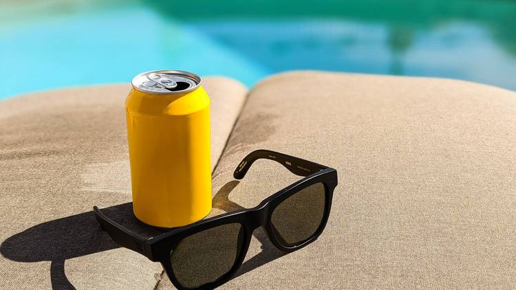 sunglasses and a beer on a pool lounger.