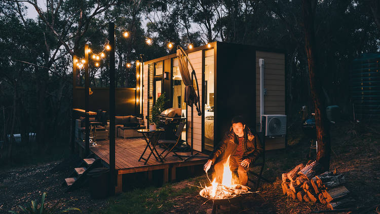 Person sits around fire at night in front of a Tiny Away cabin