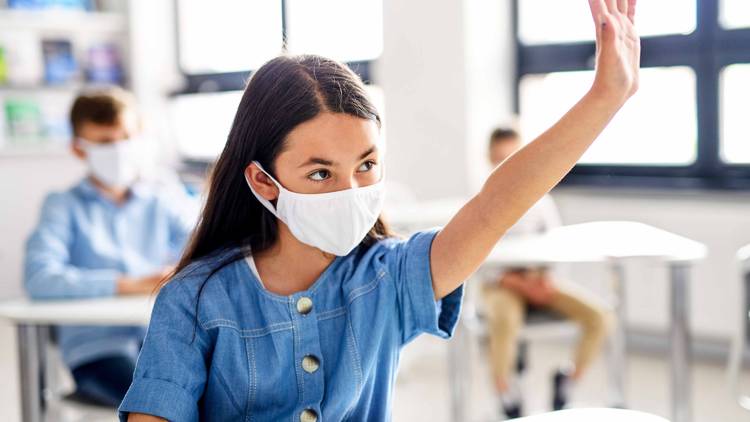 Student wearing a mask raising her hand