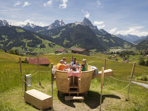 Outdoor fondue, for Gstaad campaign. A family eating fondue at a table in the Swiss countryside.