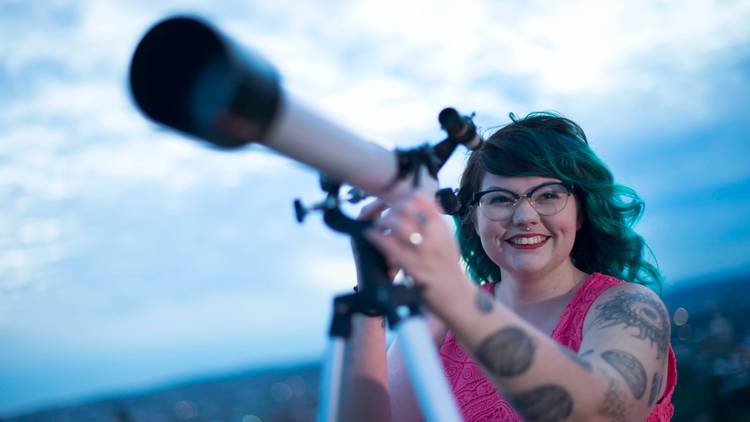 Award-winning astrophysicist and Gamilaraay woman Karlie Noon in a pink top, using a telescope