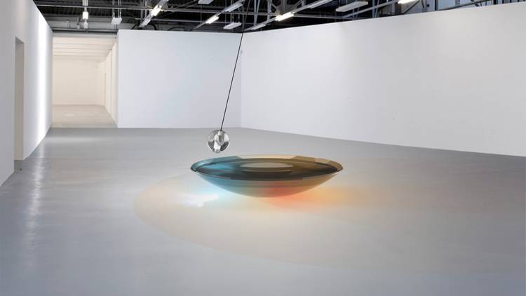 A pendulum swinging over an under-lit glass bowl