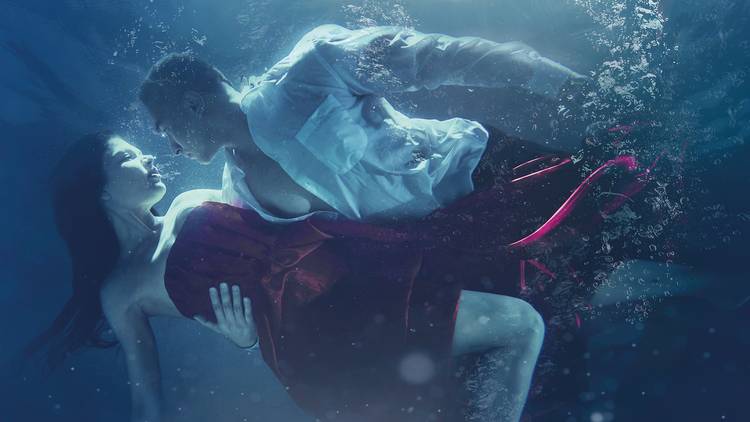 a man and woman submerged under water fully clothed