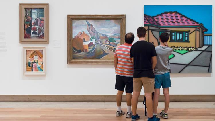 Three people looking at works on a gallery wall