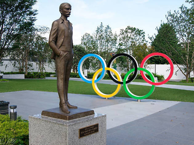 コロナに関係なく来年のオリンピック、パラリンピックは開催へ Photo: Joel Papalini/Dreamstime Olympic rings and statue of Pierre de Coubertin near the new national stadium in Tokyo