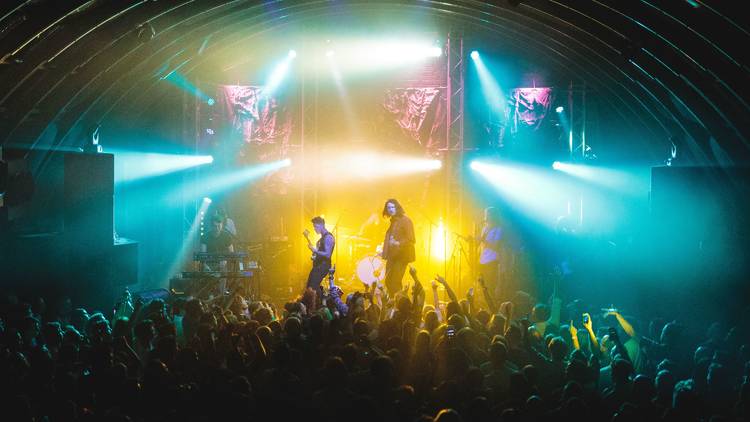 A band playing onstage to a packed crowd inside a building with a domed roof