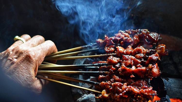 Person holding satay skewers