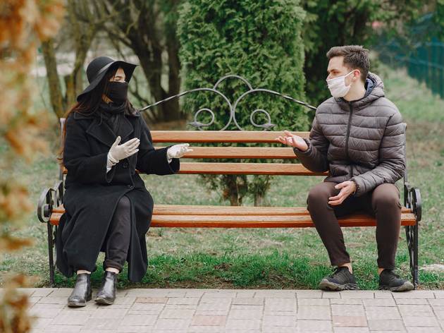 Couple outside on park bench masks Couple outside on park bench masks