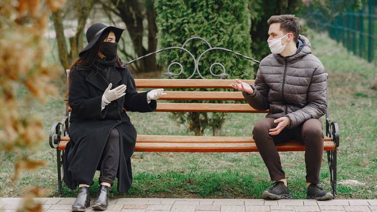 Couple outside on park bench masks