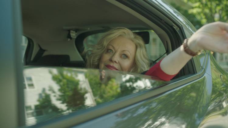 Jacki Weaver leans one arm out the back of a car as Maybelline in movie Stage Mother