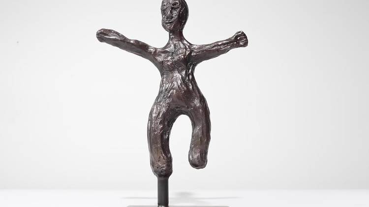 A bronze figurine of a man with arms outstretched