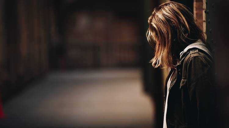 A young woman in a dark alley-like place