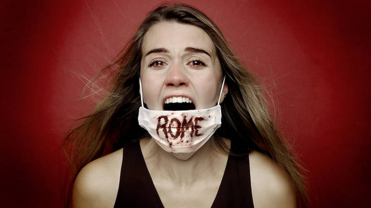 Woman screaming in mask with "Rome" written on it in blood in Rogue Ensemble Theatre Company's Titus Andronicus