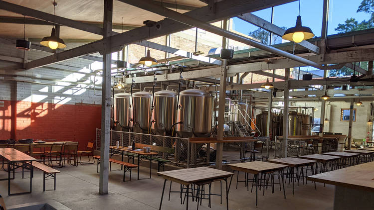 The interior of a brewery bar with open roof and silver vats