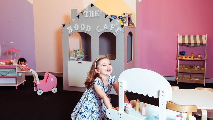 Kid laughing and interacting with the mini café and toys at The Hood Créche