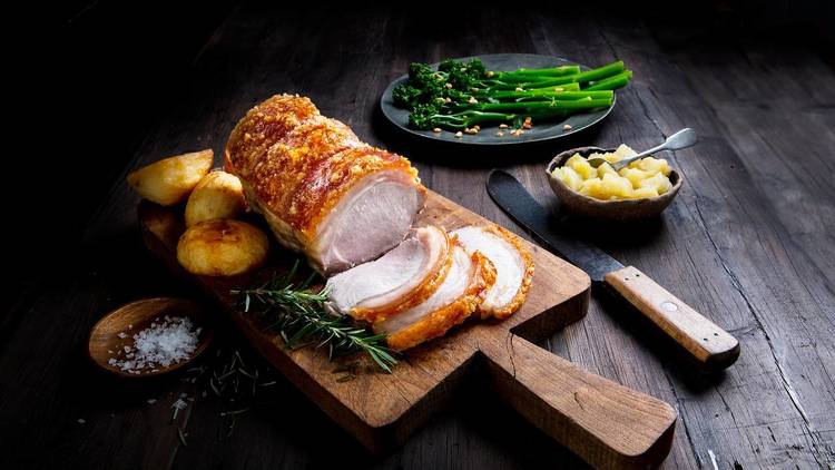 Riverview Farms - roast pork with crackling Riverview Farms roast pork with crackling sliced on a board with roast potatoes, apple sauce and steamed greens