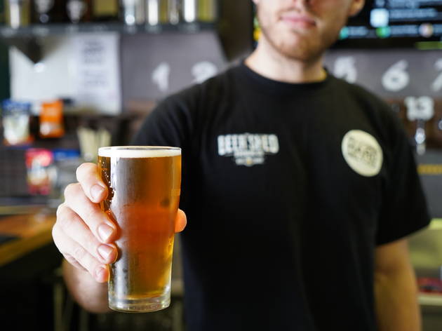 The Beer Shed Bartender holds a beer.