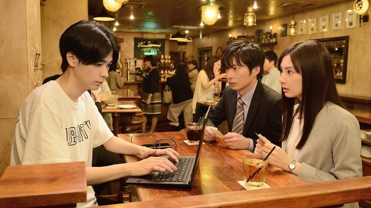 Three Japanese people in a bar with a laptop