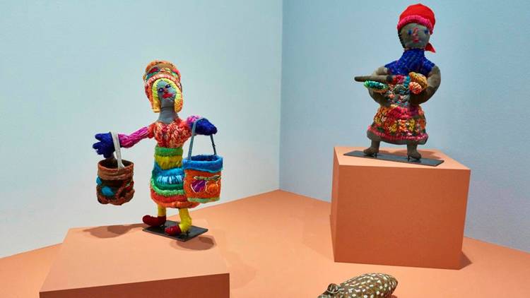 Colourful yarn sculptures of First nations women carrying dilly bags