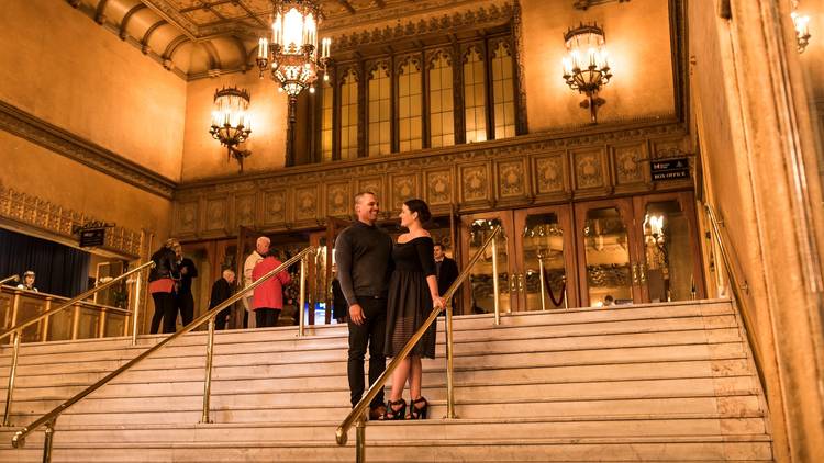 Two people standing on the golden stairs outside Regent Theatre