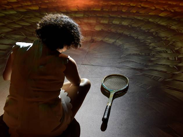 Sunshine Super Girl, Carriageworks, Sydney Festival 2021 Image from behind of Katie Beckett playing Wiradjuri woman and tennis legend Evonne Goolagong lookig at her racket on the ground