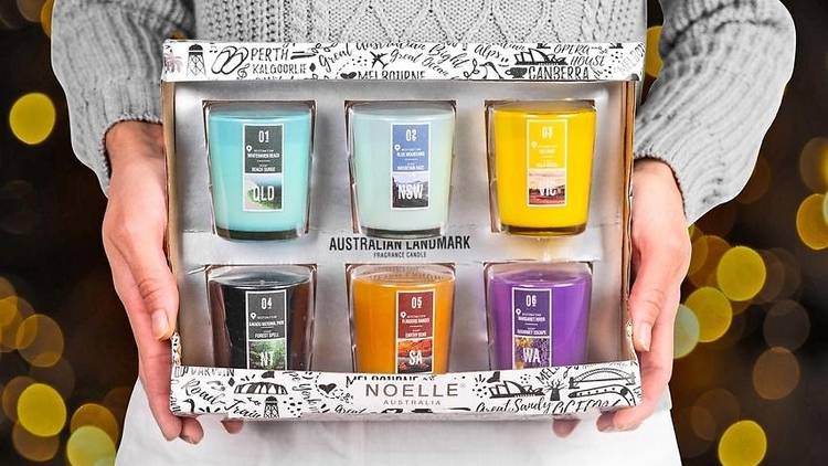 Hands holding six soy candles in a box