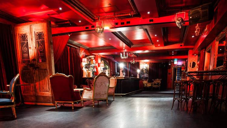 A room with red walls holds a bar and lavish vintage furniture. 