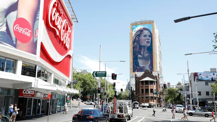 A huge mural of Nicoel Kidman on the side of a building opposite the Coca-Cola sing in the Cross