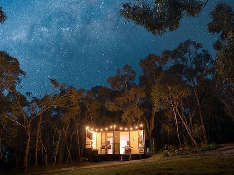 Tiny house in the forest lit up with fairylights