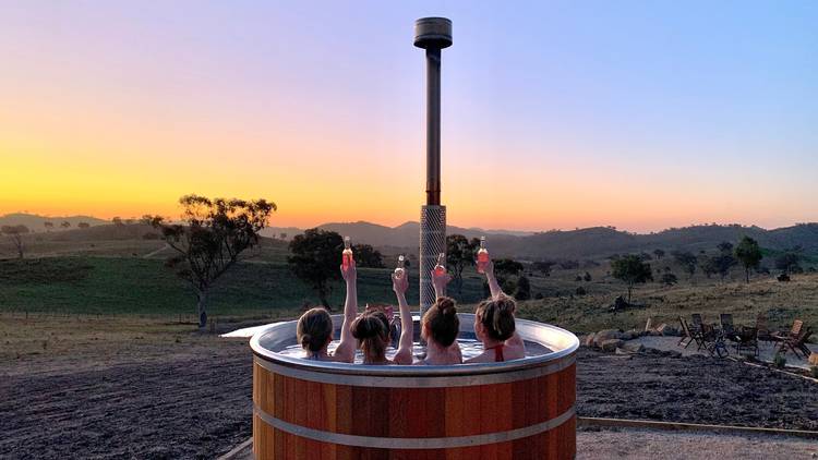 People sit in a hot tub, raising their drinks