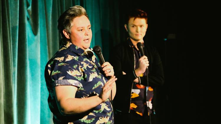 Geraldine Hickey and Rhys Nicholson holding mikes. Hickey looks like she is speaking while Nicholson looks on