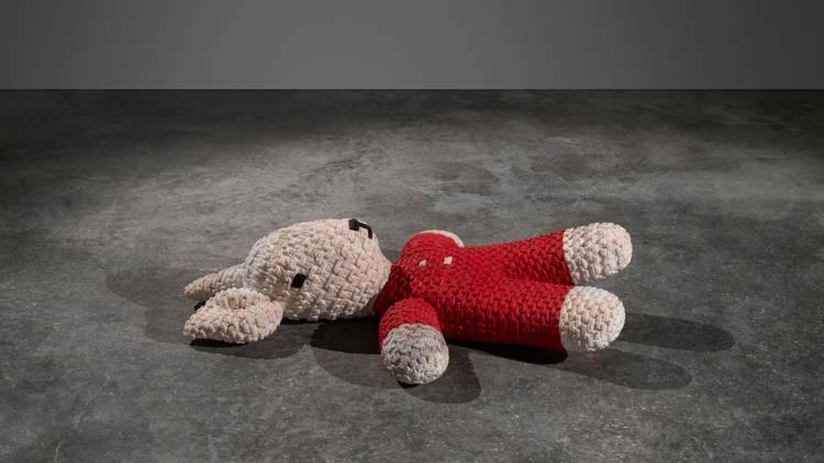 an acrylic and marble statue of a stuffed bunny toy lying on a concrete floor