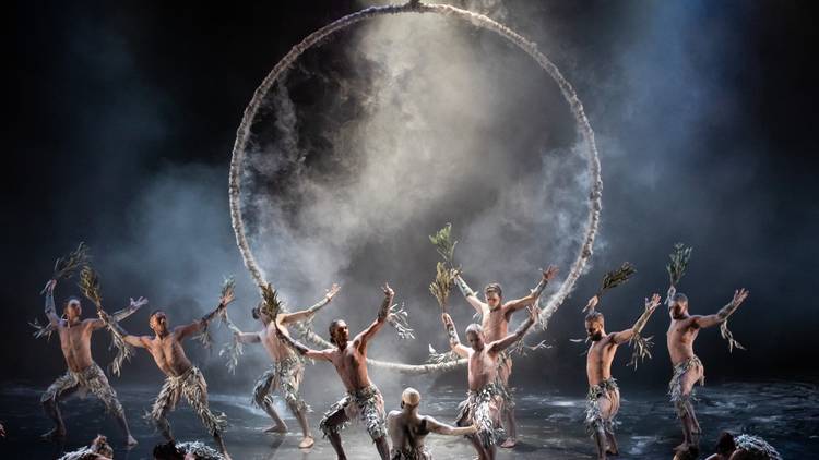 Bangarra dancers perform in smoke in front of a huge circle hung above the stage