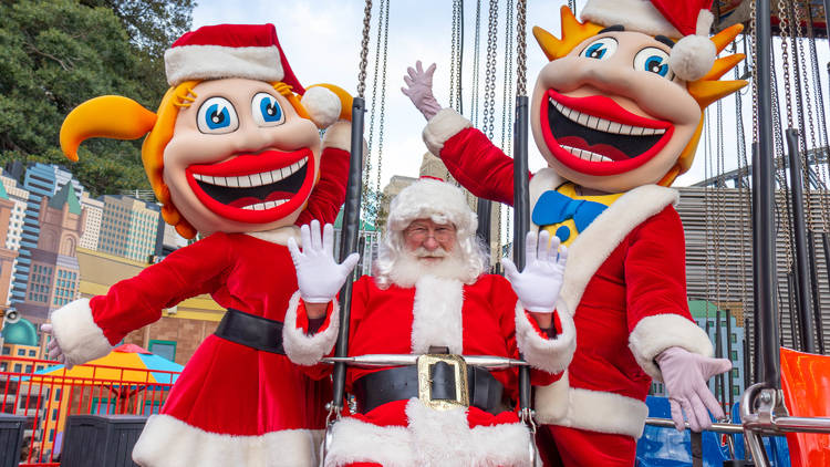 Santa rides the spinning chairs with two big smiling mascots