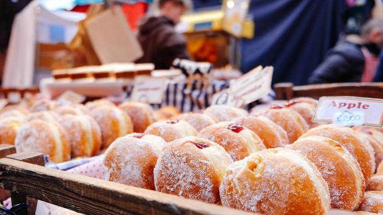 Trays of doughnuts at market stall.