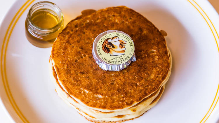 A stack of pancakes with syrup and Pepe Saya butter