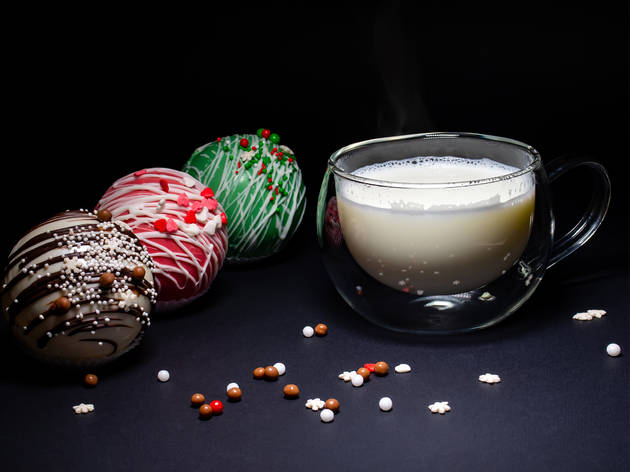 Bombas de chocolate Taza de leche caliente con bolas de chocolate a un lado