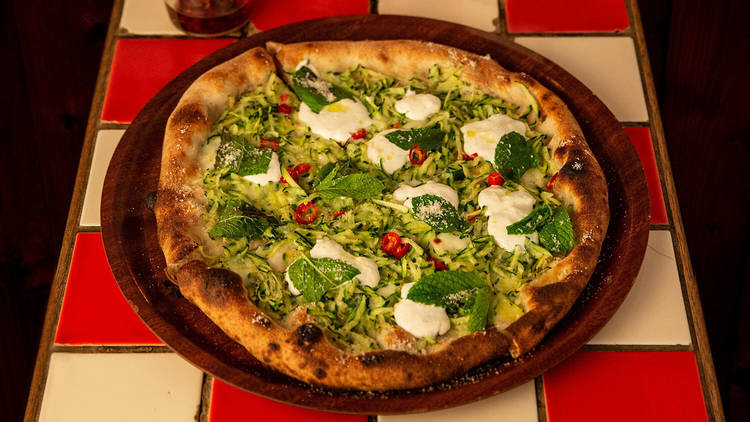 A zucchini, lemon, chilli, garlic and mint pizza on a tiled tabletop