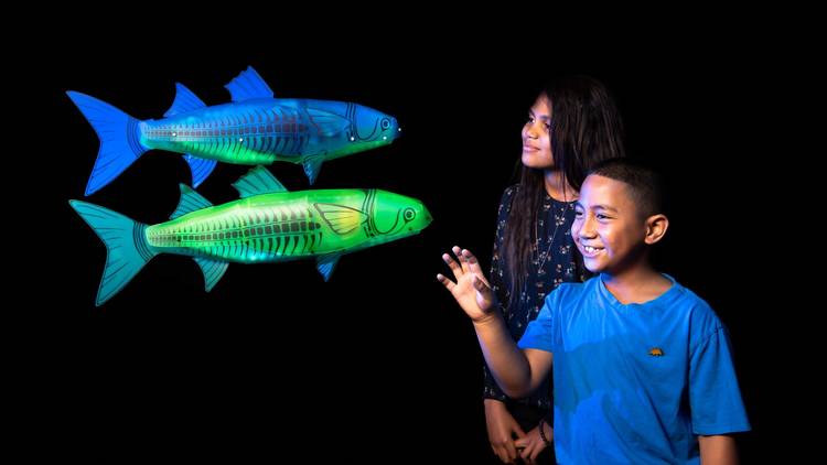 Children pose with illuminated puppets of fish