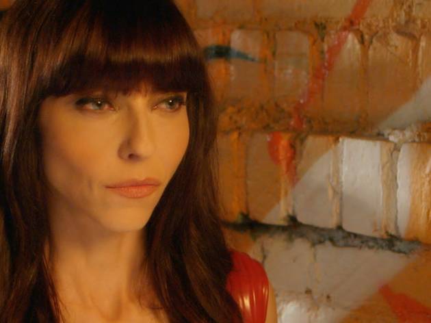 Juliet Landau, A Place Among The Dead 2021 Buffy star Juliet Landau, who played Drusilla, in a shiny red sleeveless top against a bright-painted brick wall