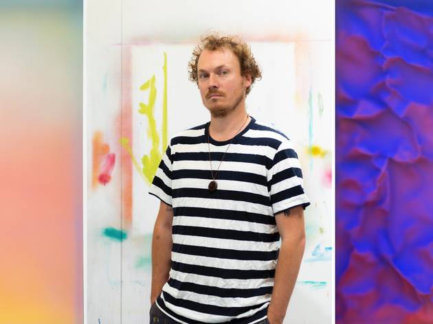 Daniel O’Toole, Deliquescent Light, Curatorial+Co 2021 MUltimedia artist Daniel O’Toole, wearing a striped black and white t-shirt, framed by his colourful art