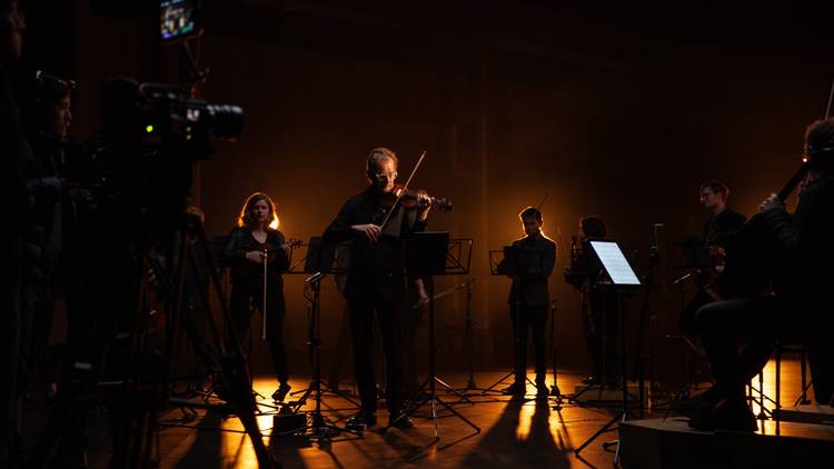 Richard Tognetti and the ACO filming their digital ACO StudioCasts with moody orange back lighting