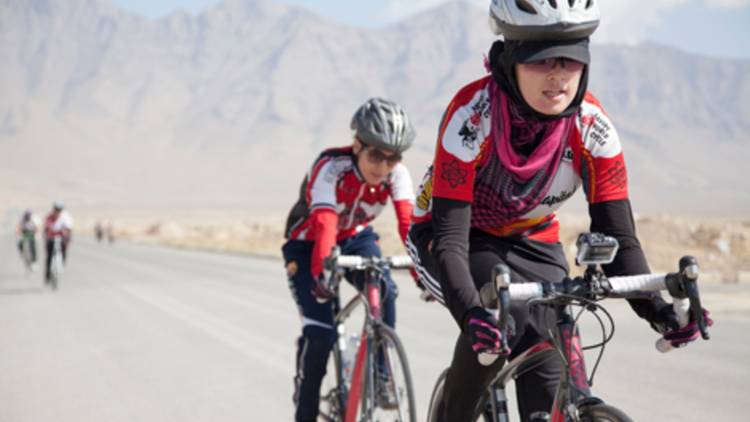 Afghan women riding bikes against a mountainous backdrop 