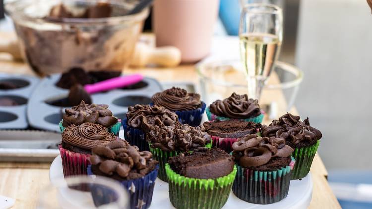 Plate of decorated cupcakes next to glass of bubbly.