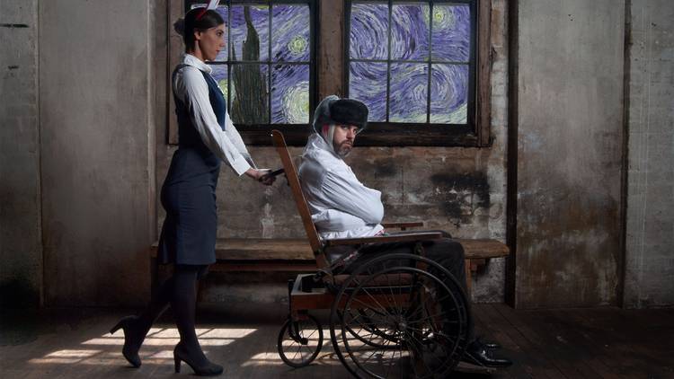 An actro Plays Vincent Van Gogh in a wheelchair after cutting his ear off, pushed by a nurse