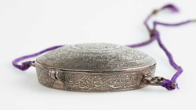 A silver, engraved war amulet on purple thread from 1800s Persia