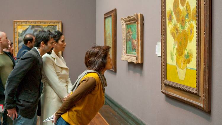 Gallery viewers looking closely at Vincent Van Gogh's 'Sunflowers'