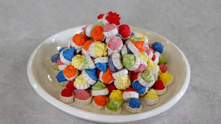 Ceramic fairy iced biscuits in multiple bright colours on a plate