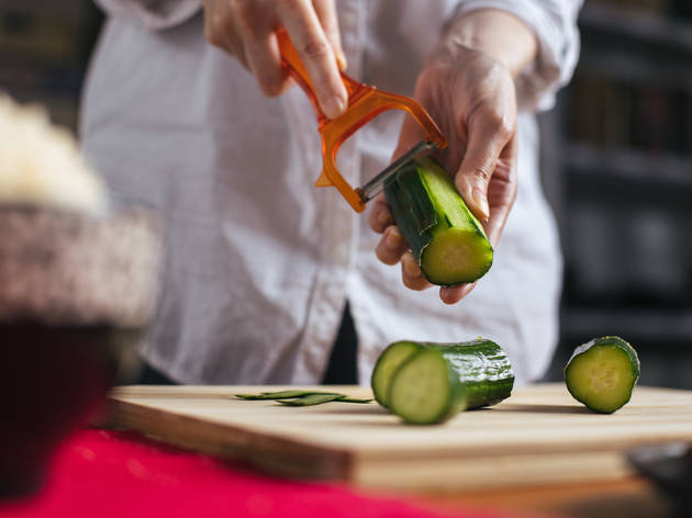 Female chef peeling cucumber in a home kitchen Female chef peeling cucumber in a home kitchen