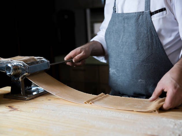 Chef rolling homemade pasta through pasta machine Chef rolling homemade pasta through pasta machine